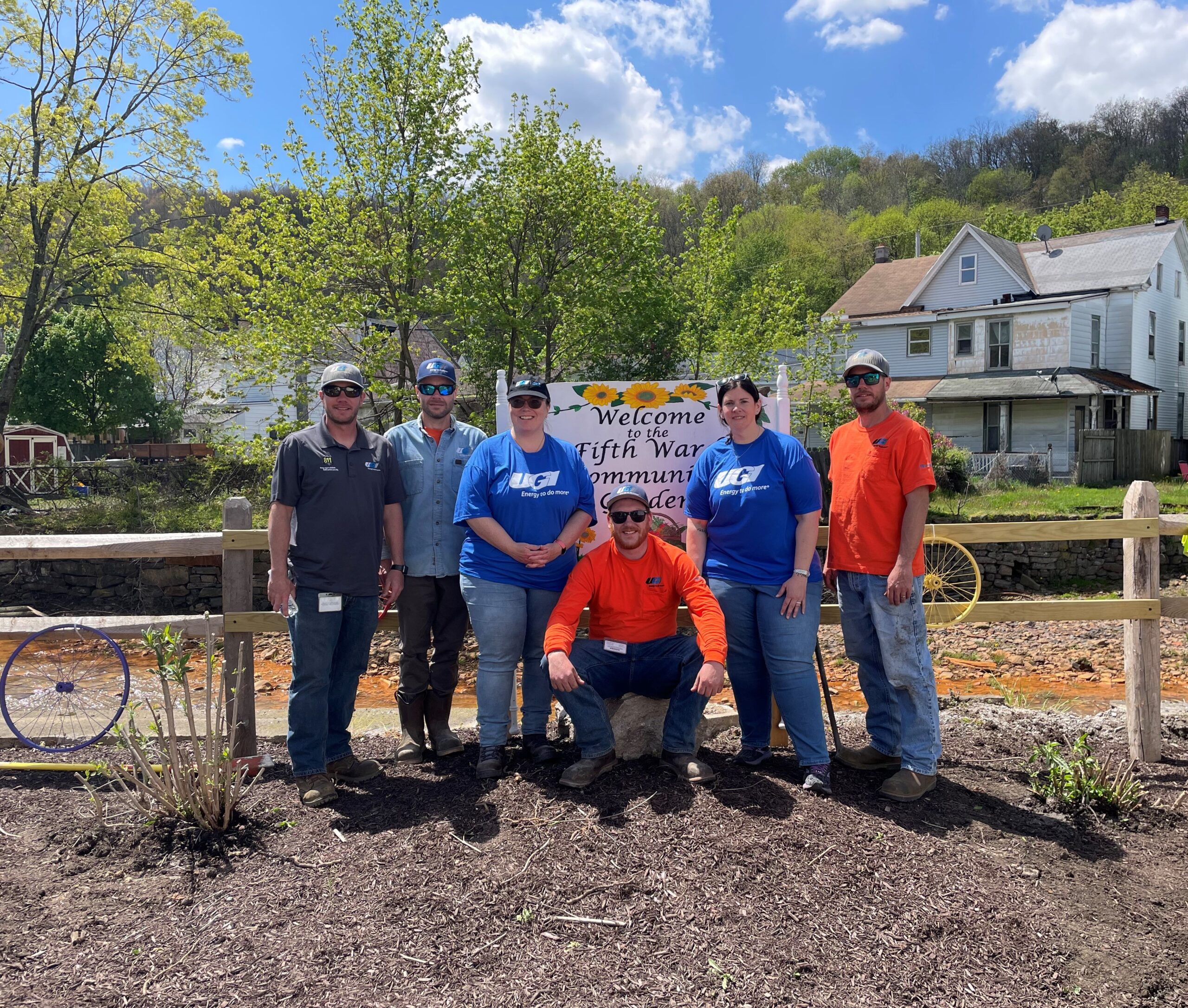 UGI employees stand in front of Fifth Ward Community Garden sign
