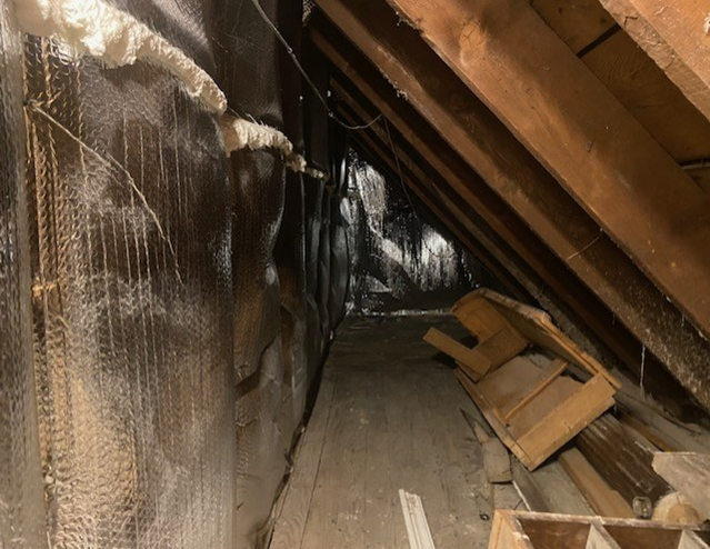 Polystyrene board and foam weather stripping insulating an attic.