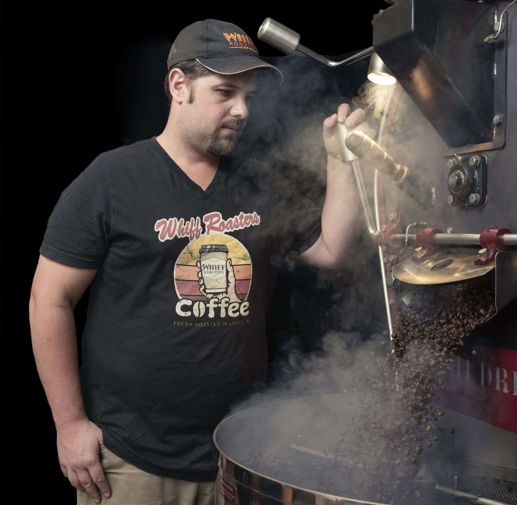 Man operating coffee roasting bean machine.