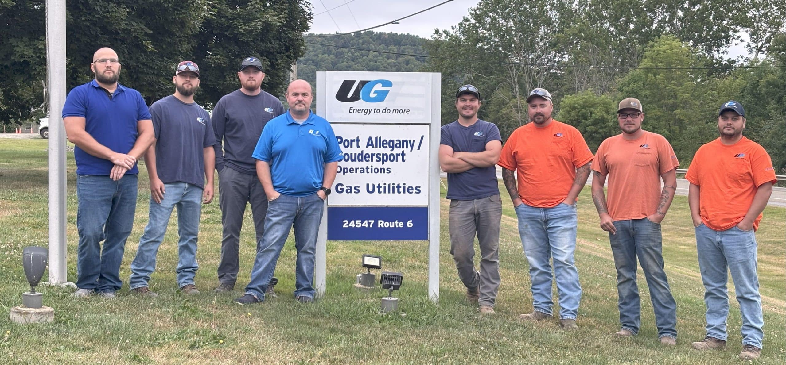 Employees who assisted in the crash standing next to a sign that says Port Allegany.